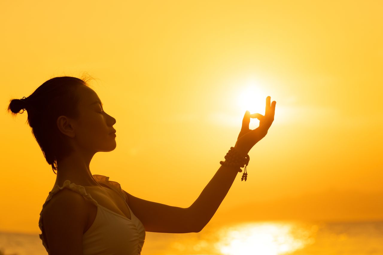 Crafting Captivating Headlines: Your awesome post title goes here Silhouette of a woman meditating by the sea during a vibrant sunset, creating a peaceful atmosphere.